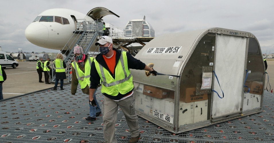 UPS employees move one of two shipping containers containing the first shipments of the Pfizer and BioNTech Covid-19 vaccine on a ramp at UPS Worldport in Louisville, Kentucky on Sunday, December 13, 2020.